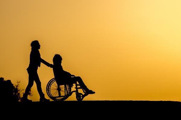 Puesta de sol en la que se refleja la sombra de una persona llevando la silla de ruedas de otra