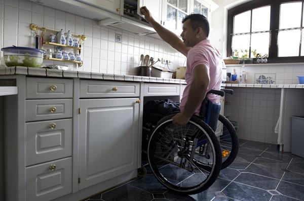 Persona en silla de ruedas en la cocina de su casa, adaptada a sus necesidades